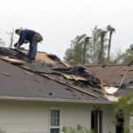 Roof covered with debris causing damage while roofing contractors quickly begin repairs