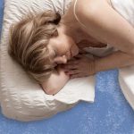 Woman sleeping peacefully on LOFE organic buckwheat pillow with cool blue background