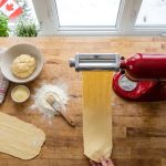 Top view of a KitchenAid mixer with a pasta roller in a bright kitchen.