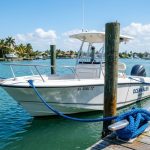 White motorboat tied to wooden dock with blue lines in Florida.