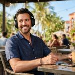 A man listening to wireless headphones on a sunny Florida beach.